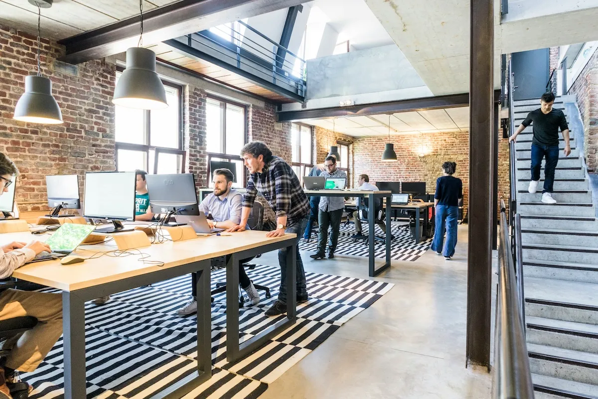 A small agency team working at shared desks in an open warehouse-style studio office.