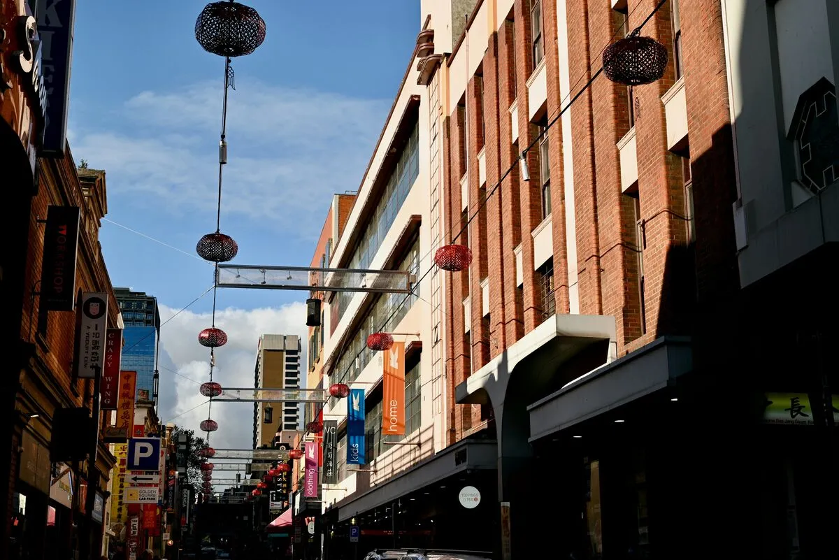 Red lanterns strung above a Melbourne Chinatown street lined with restaurants and shopfronts.