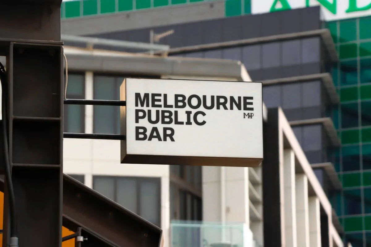 A hanging 'Melbourne Public Bar' shopfront sign against a city building in Melbourne.