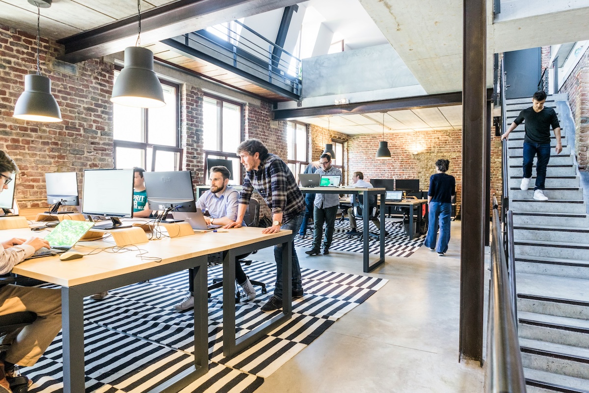 A small agency team working at shared desks in an open warehouse-style studio office.